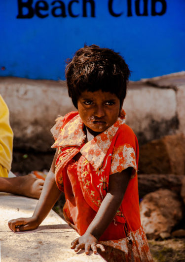 portrait photography of a little Indian girl in a red dress in front of a blue wall - by Mike Rüpping - friendmade.fm